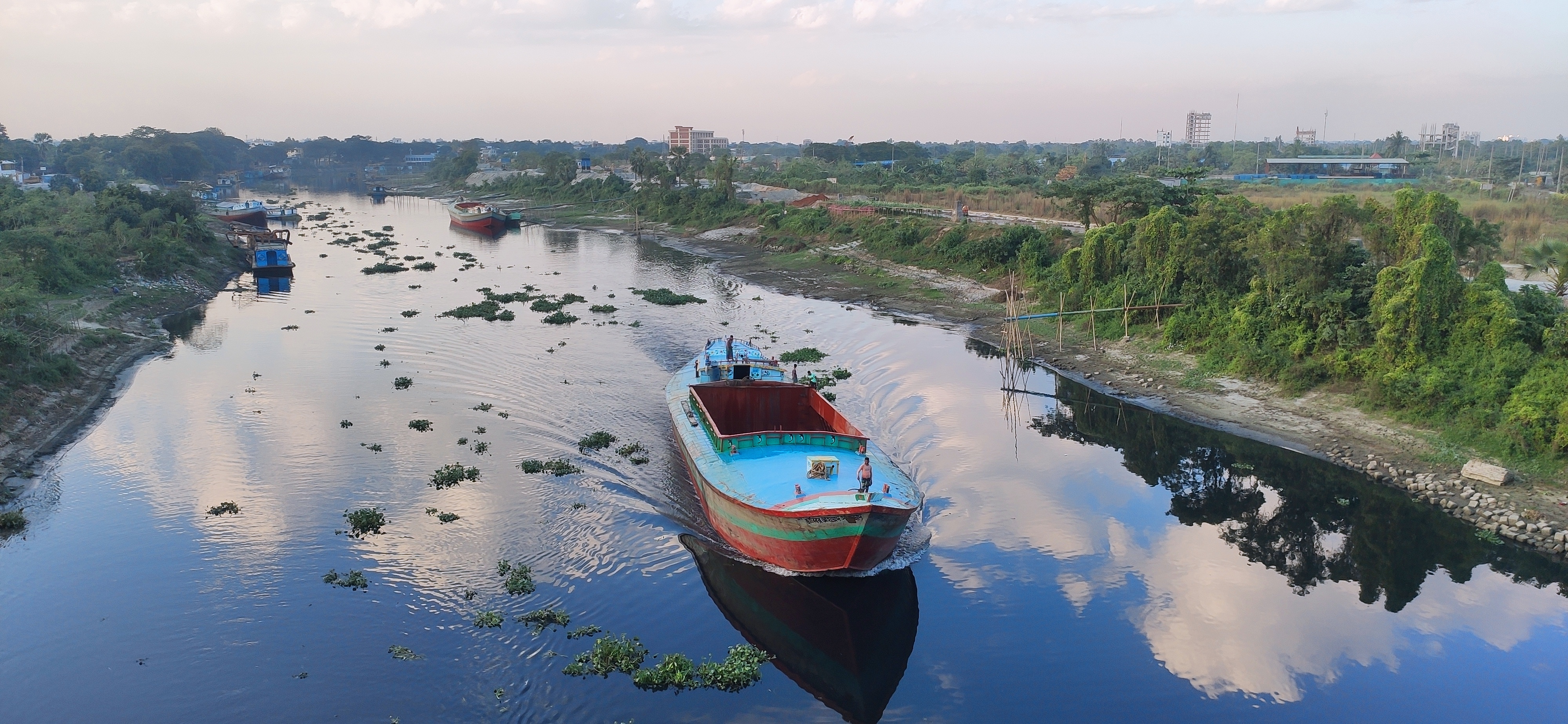 A cargo vessel on a river at dawn.